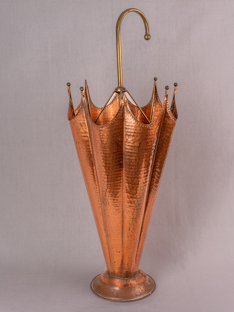 Mid-century French umbrella stand with hammered copper, brass handle, and pointed edges on light gray background.