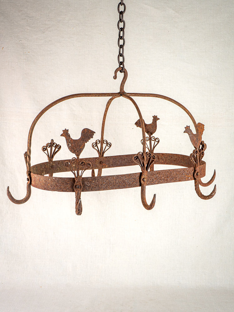 Vintage French wrought iron pot rack with rooster motif, floral cutouts, and hanging hooks.