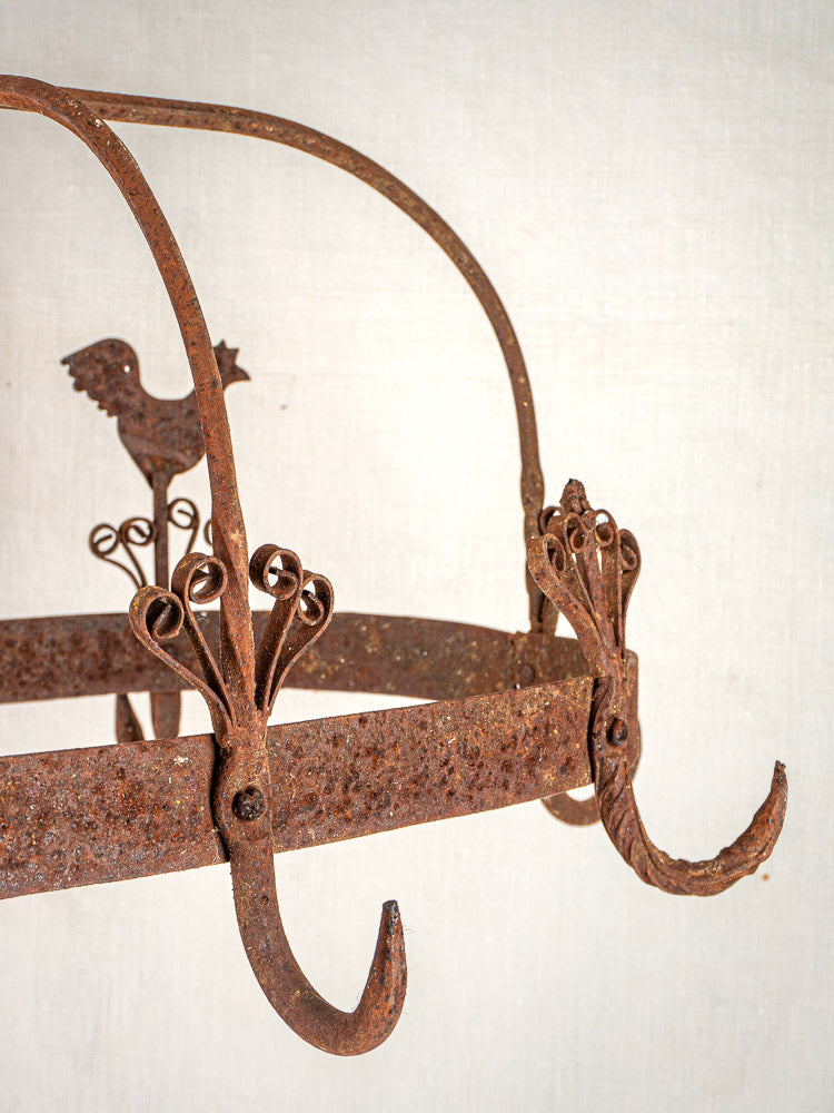 Vintage French wrought iron pot rack with ornate hooks and decorative rooster motif, classic country style.