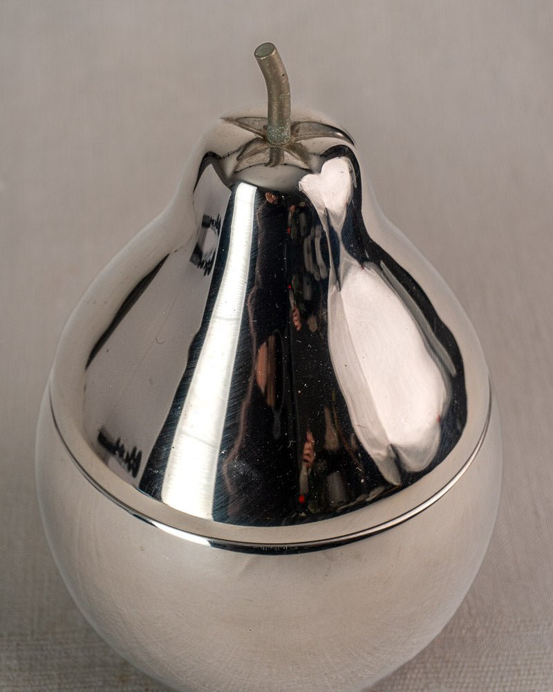 Mid-century stainless steel French pear-shaped ice bucket with stem, reflective finish on light fabric surface.