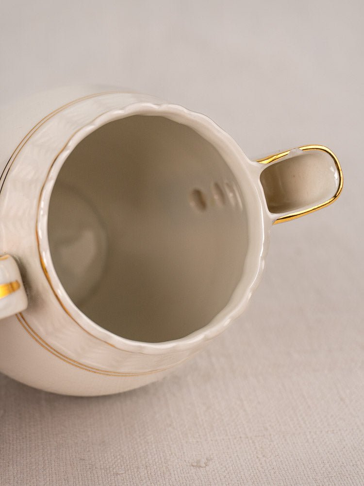 Antique French Limoges porcelain sugar bowl with twin handles and gold trim, empty interior visible.
