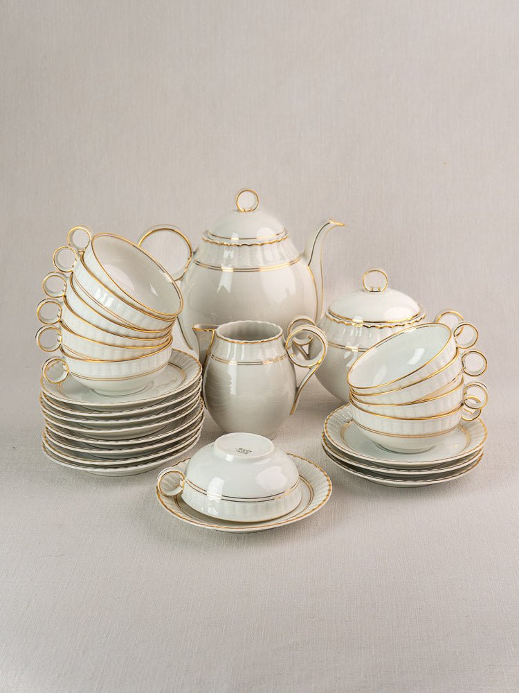 Antique French Limoges Bernardaud 26-piece porcelain tea set with gold trim on light surface.