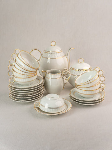 Antique French Limoges Bernardaud 26-piece porcelain tea set with gold trim on light surface.