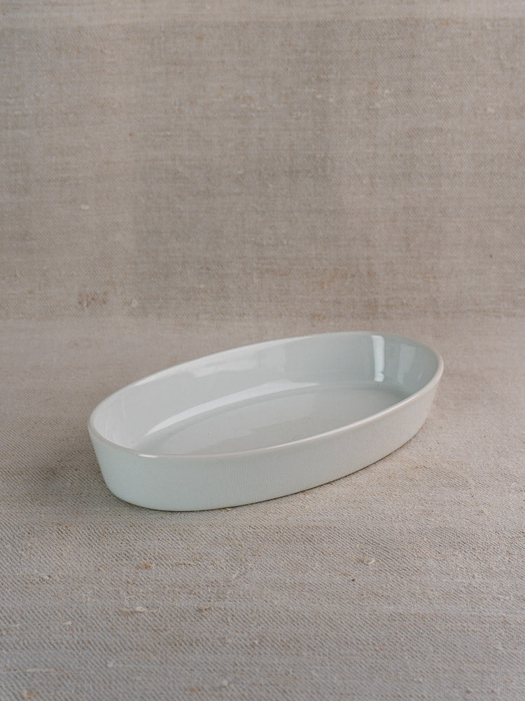 Vintage French CNP white porcelain oval serving dish on a textured beige fabric surface.