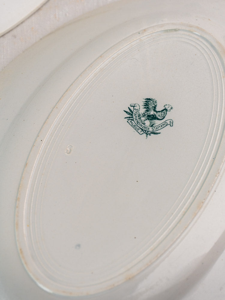 Antique French Saint Amand Muguet faience platter set undersides with green eagle crests and textured rims.