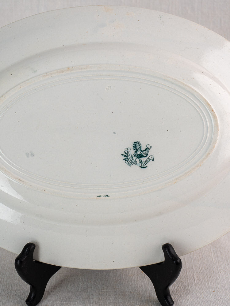 Antique French Saint Amand faience platter on black stand, underside with green lion and shield mark.