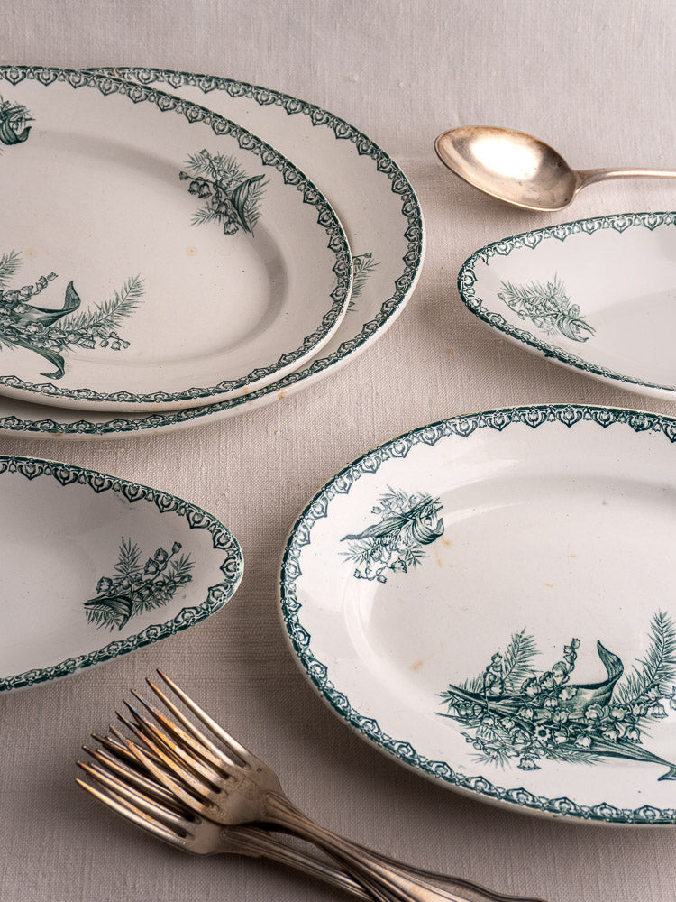 Set of five antique French Saint Amand Muguet faience platters, stacked with silver flatware.