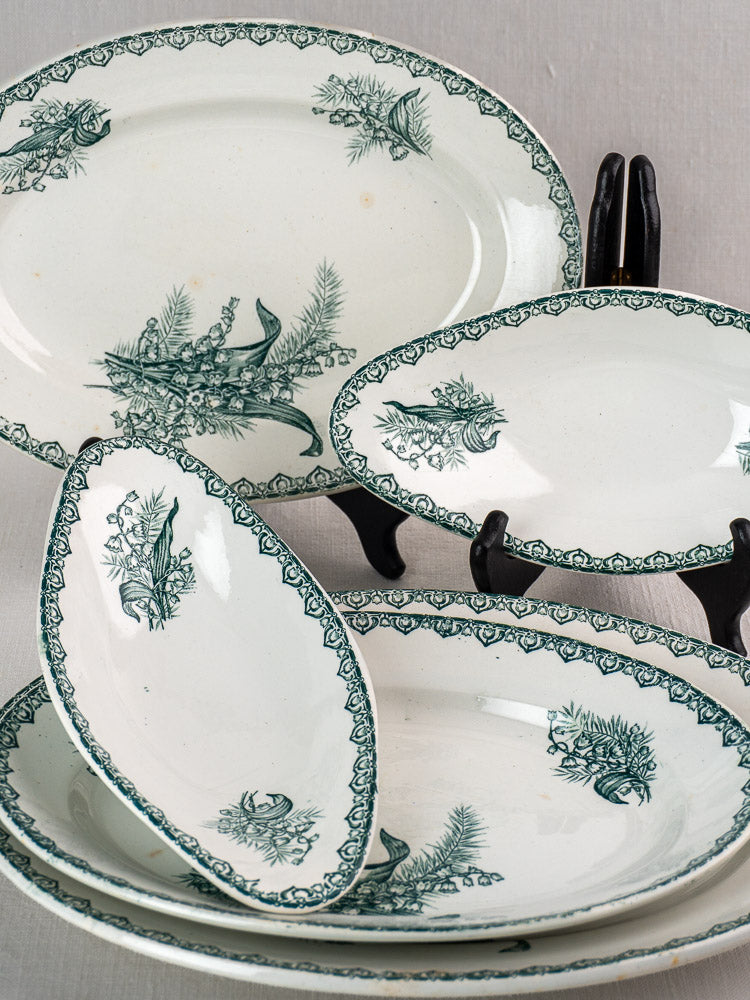 Antique French Saint Amand Muguet faience platter set with green floral designs on white ceramic, displayed on gray surface.