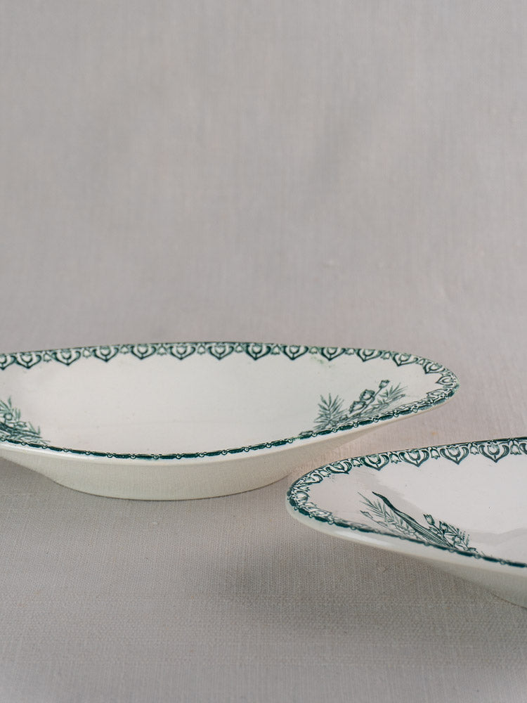 Antique French Saint Amand faience dishes with green rim patterns on light gray fabric.