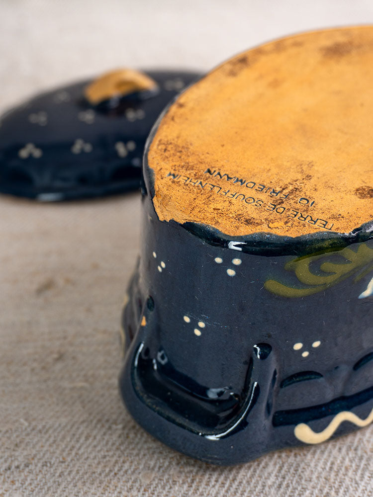 Antique French Soufflenheim terrine in cobalt blue with duck motif, yellow-orange base, lid set behind on beige fabric.
