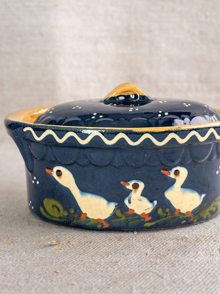 Antique French Soufflenheim cobalt blue covered terrine with duck motif and yellow-green accents on beige fabric.