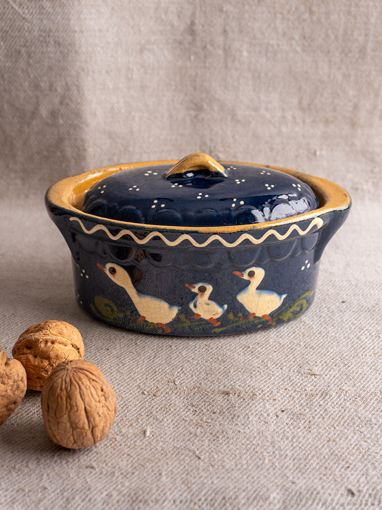 Antique French Soufflenheim cobalt blue covered terrine with duck motif, mid 20th century, on beige cloth with walnuts.