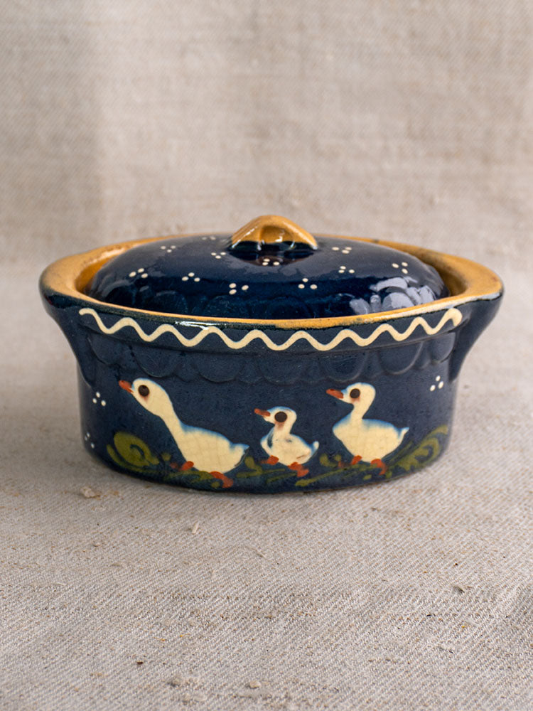 Antique French Soufflenheim covered terrine in cobalt blue with duck motif, yellow rim on textured beige fabric.