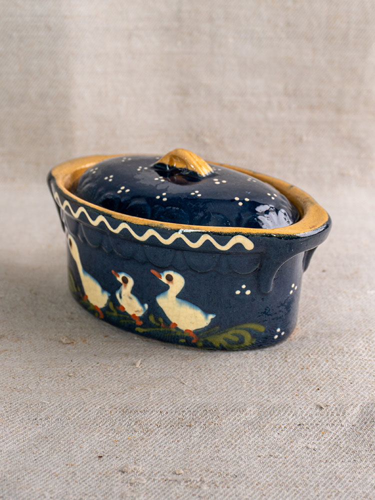 Antique French Soufflenheim covered terrine in cobalt blue with white duck motif and yellow trim on beige fabric.