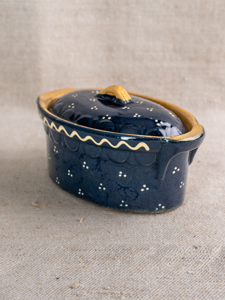 Antique French Soufflenheim cobalt blue covered terrine with duck motif, yellow wavy patterns, on beige textured fabric.