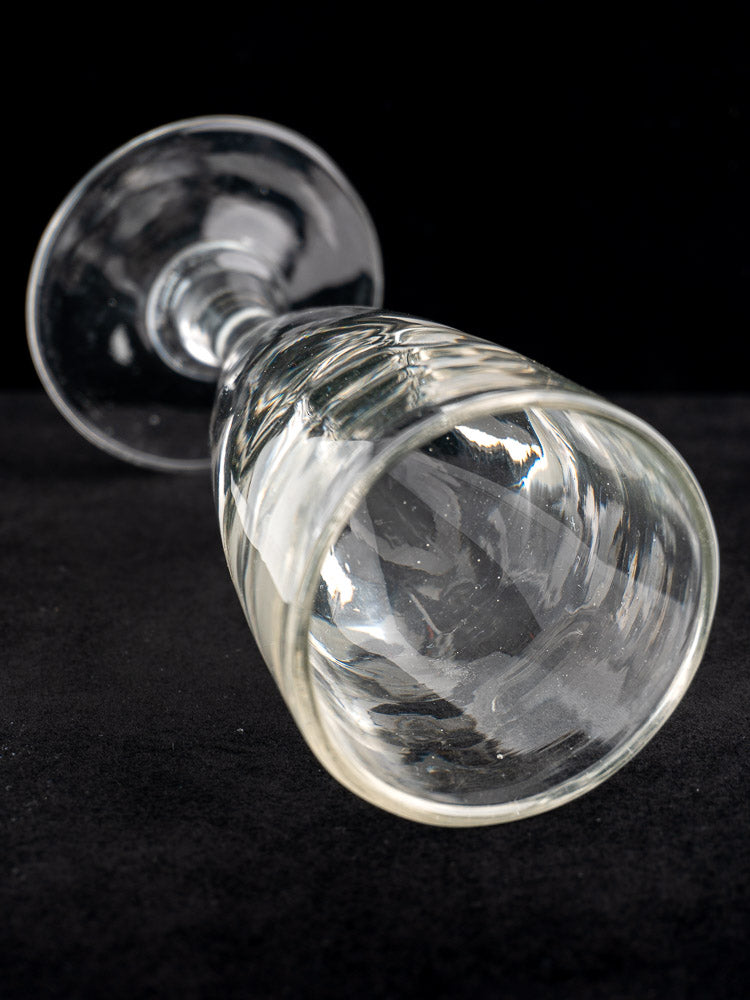 Set of four antique French uranium absinthe glasses, hand-blown Ouraline, on a black surface, one glass on its side.