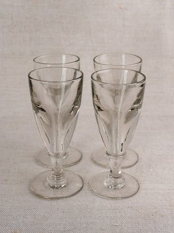 Set of four antique French uranium absinthe glasses, late 19th century, hand-blown ouraline glass on light textured surface.