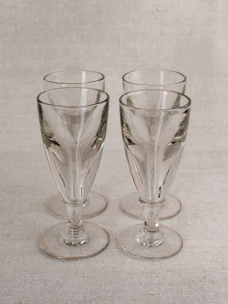 Set of four antique French uranium absinthe glasses, late 19th century, hand-blown ouraline glass on light textured surface.
