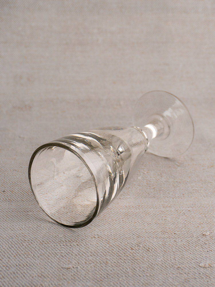 Set of four antique French uranium absinthe glasses, hand blown, shown empty on a textured light surface.