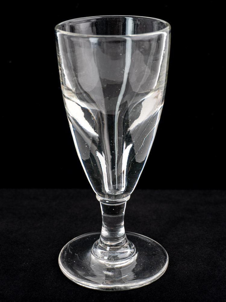 Antique French uranium absinthe glasses, hand-blown Ouraline, late 19th century, half-filled with water, black background.