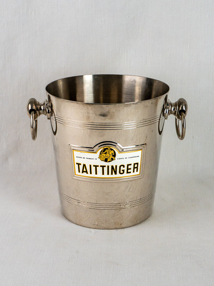 Vintage French Taittinger champagne bucket in silver-plated metal with side handles on a light background.