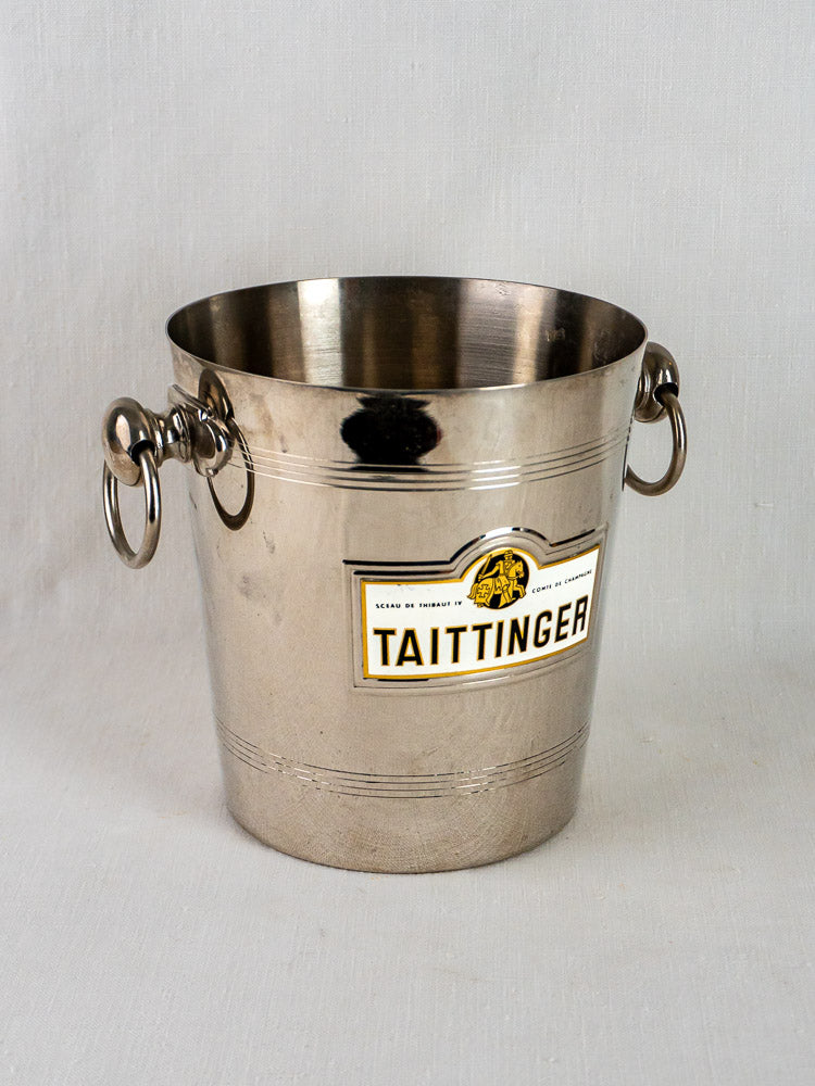 Taittinger vintage French plated wine cooler with side handles and signature label on plain light background.