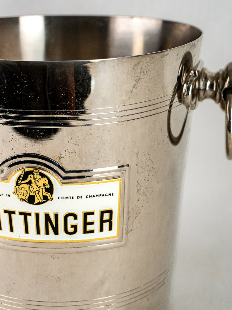 Close-up of Taittinger champagne bucket with partial label and right-side handle visible.