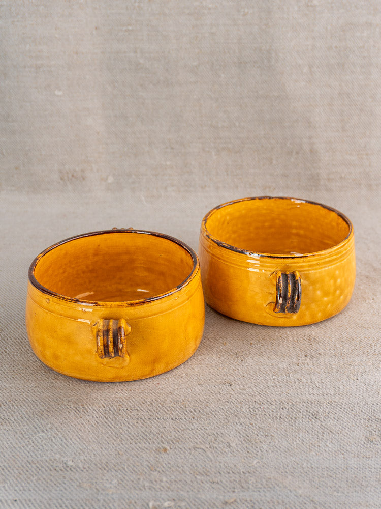 Pair of round yellow vintage French Vallauris ceramic bowls with decorative handles and glossy brown-accented glaze.