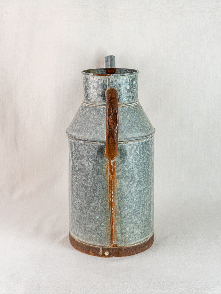 French vintage galvanized zinc watering can with central handle and weathered patina, subtle rust accents.