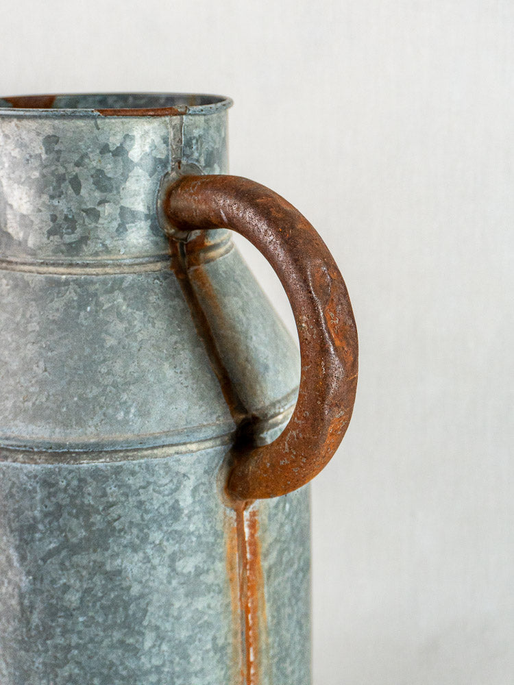Weathered French galvanized zinc arrosoir vintage watering can with rustic metal handle, neutral background.
