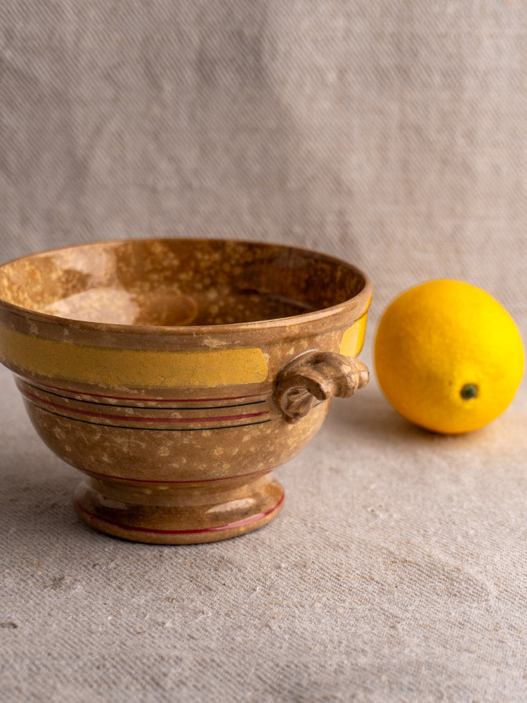 Antique French faience bowl by HB et Cie, yellow and red bands on brown ceramic, displayed with lemon on beige surface.