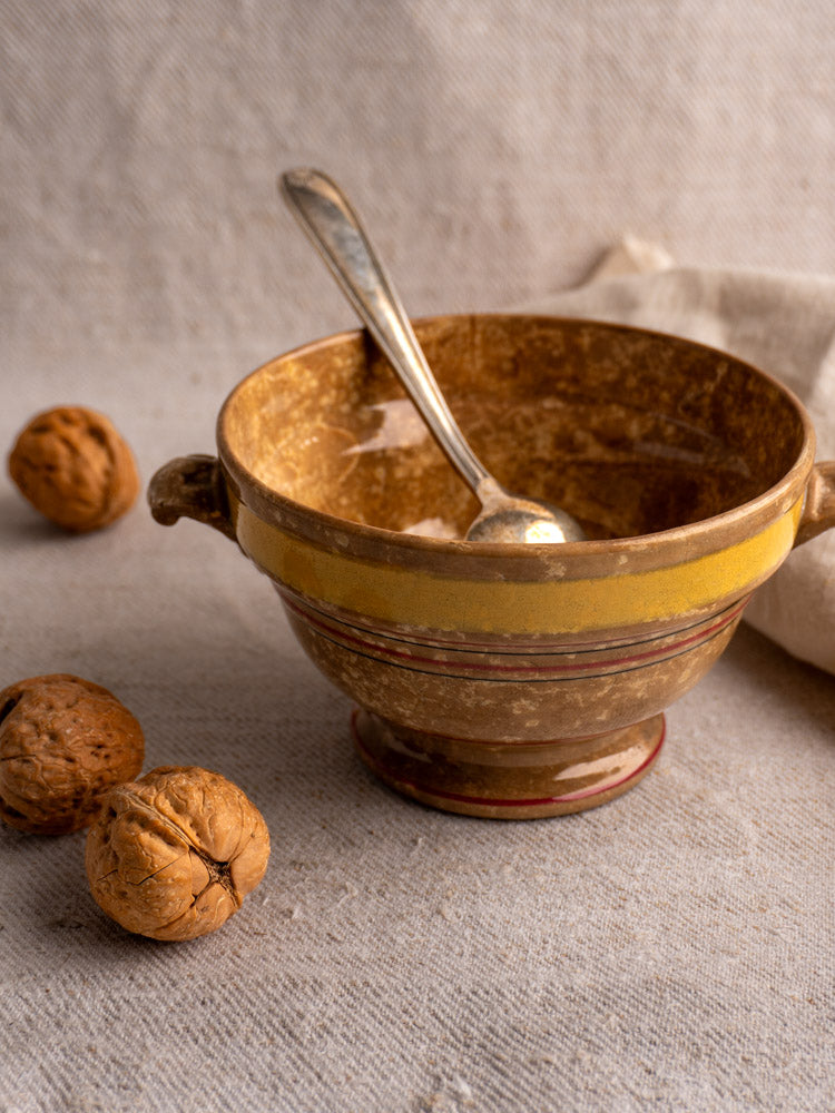 Antique French faïence bowl by HB et Cie, brown jaspé glaze, with spoon and walnuts on beige fabric.