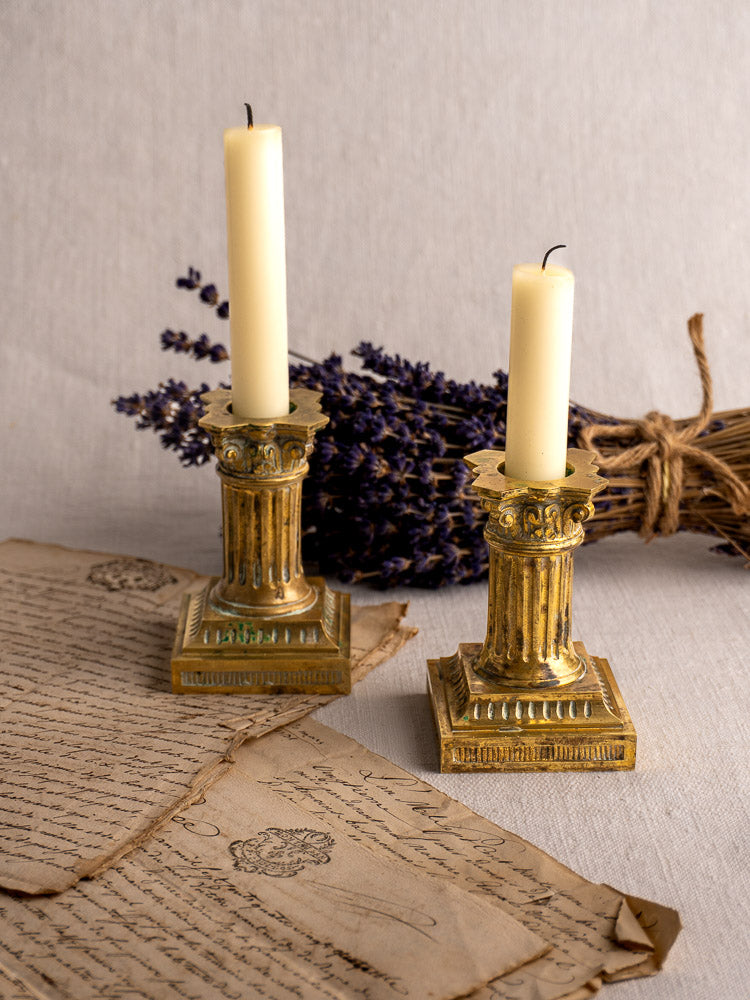 Louis XVI antique French gilded brass candlesticks with lit candles on handwritten letters, dried lavender in background.