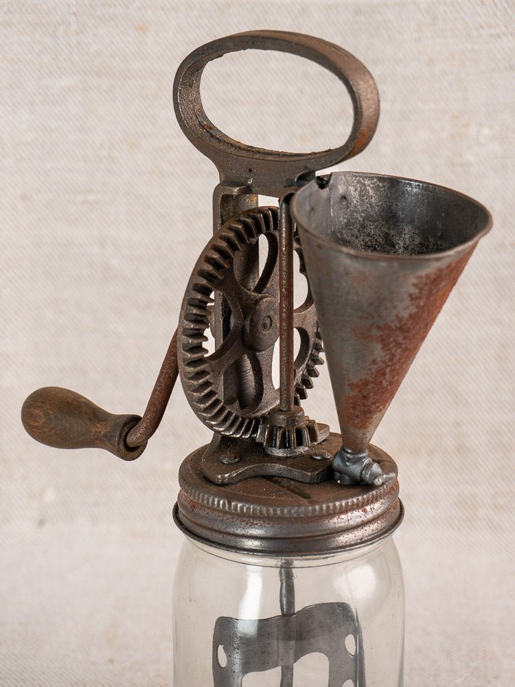 Antique French mayonnaise maker, circa 1900, with cast iron crank and metal funnel on glass jar.