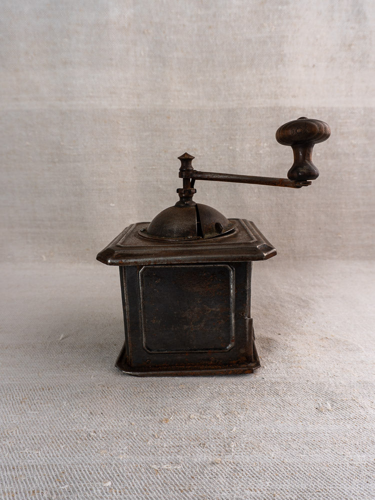 Antique French Peugeot Frères tinned steel coffee mill with wooden handle on light textured surface.