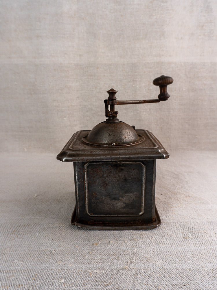 Antique French Peugeot Frères coffee mill in tinned steel with aged patina and hand crank on fabric.