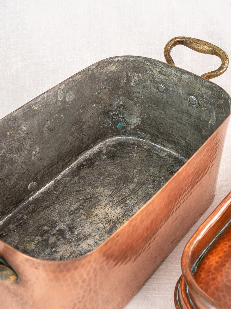 Rectangular copper Dutch oven with tarnished interior and brass handles beside a 19th-century French copper daubière.