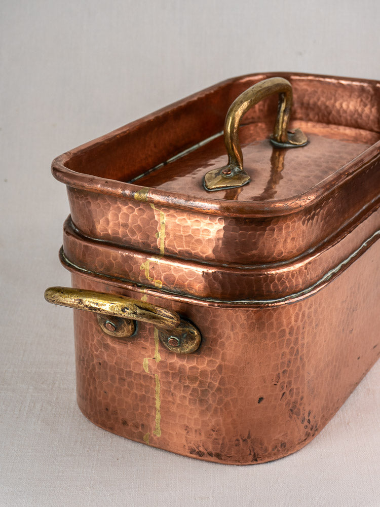 Large antique French copper daubière with brass lid, side handles, and soldered seam on a light-colored surface.