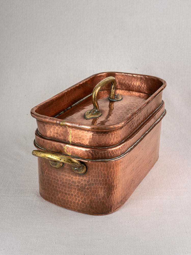 Large antique French copper daubière with brass handles and lid, hand-hammered, displayed on light fabric.