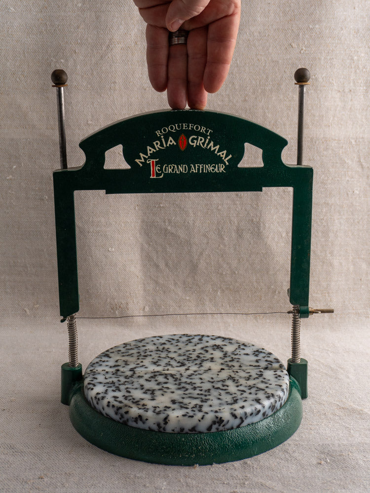 Vintage French Roquefort cheese cutter by Maria Grimal, 1960s, marble base and wire, neutral textured fabric background.