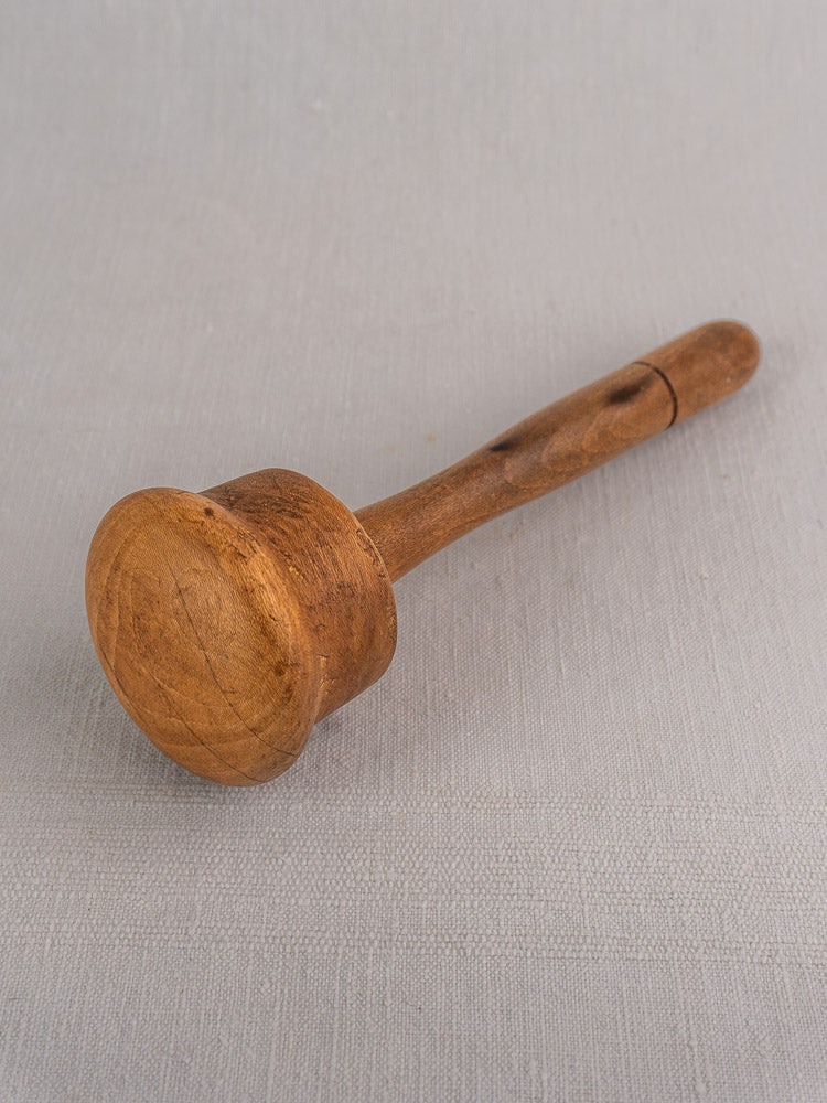 Set of three antique French turned hardwood mallets displayed on a light gray fabric surface.