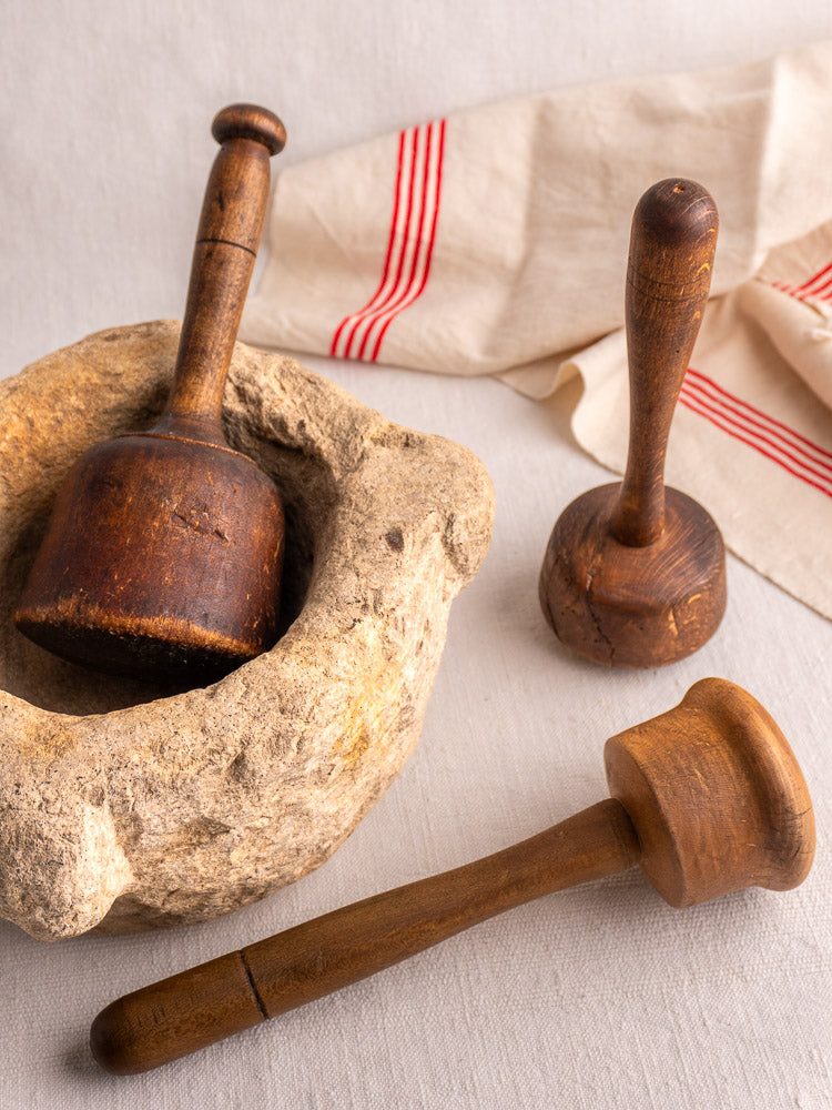 Set of three antique French turned hardwood mallets displayed on a white cloth with red stripes.