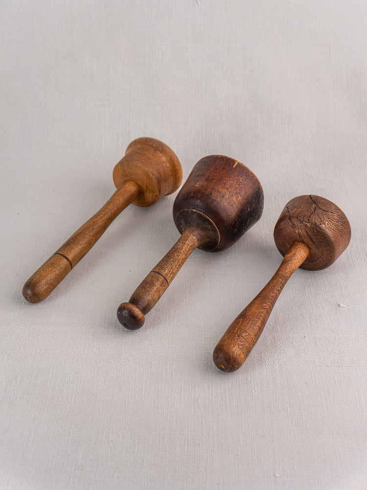 Set of three antique French turned hardwood mallets with unique grain, displayed on light gray fabric.