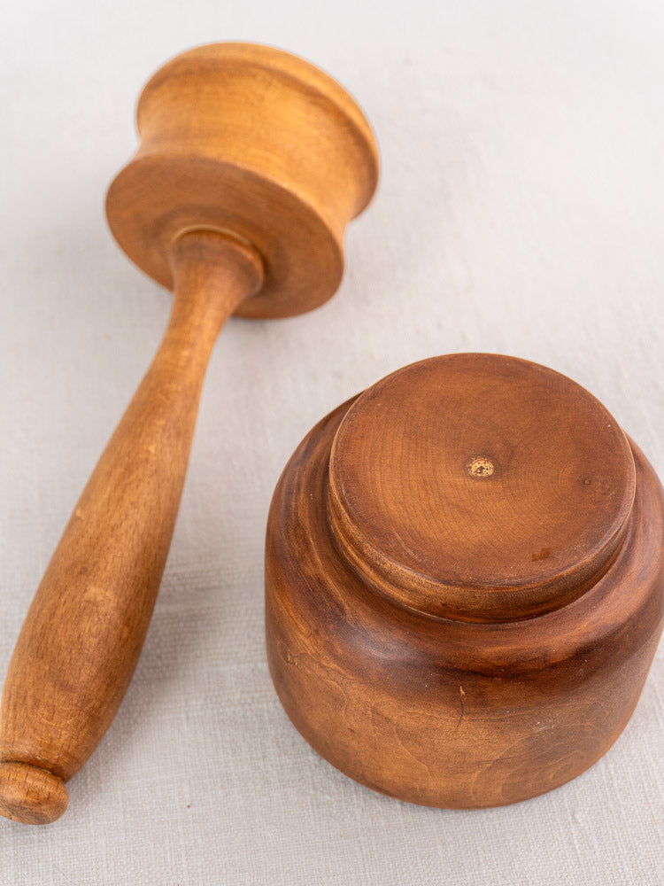 Antique French wooden mortar and pestle, turned hardwood, early-mid 20th century, on light textured surface.