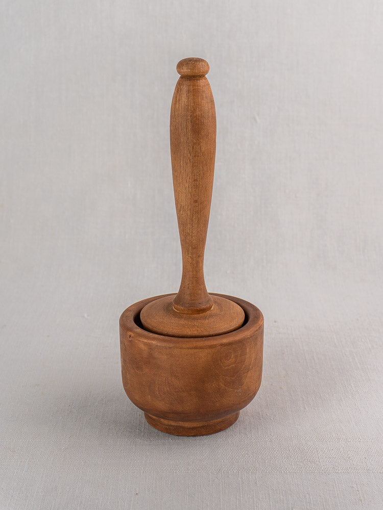 Antique French wooden mortar and pestle, early-mid 20th century, upright on light gray background.