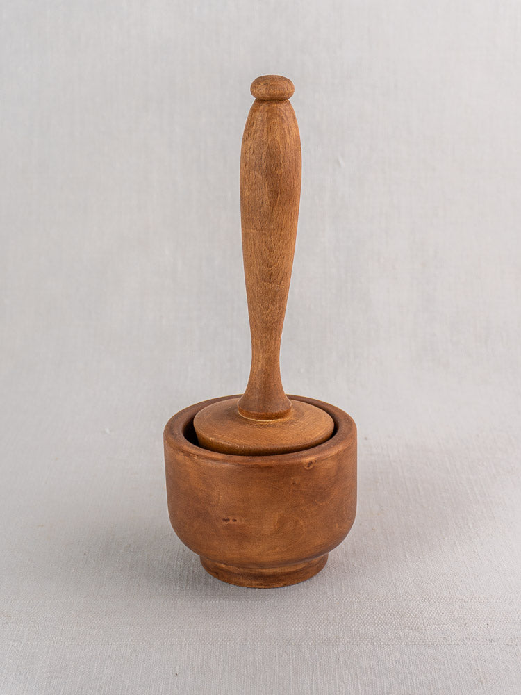 Antique French wooden mortar and pestle in turned hardwood, early to mid 20th century, on light gray surface.