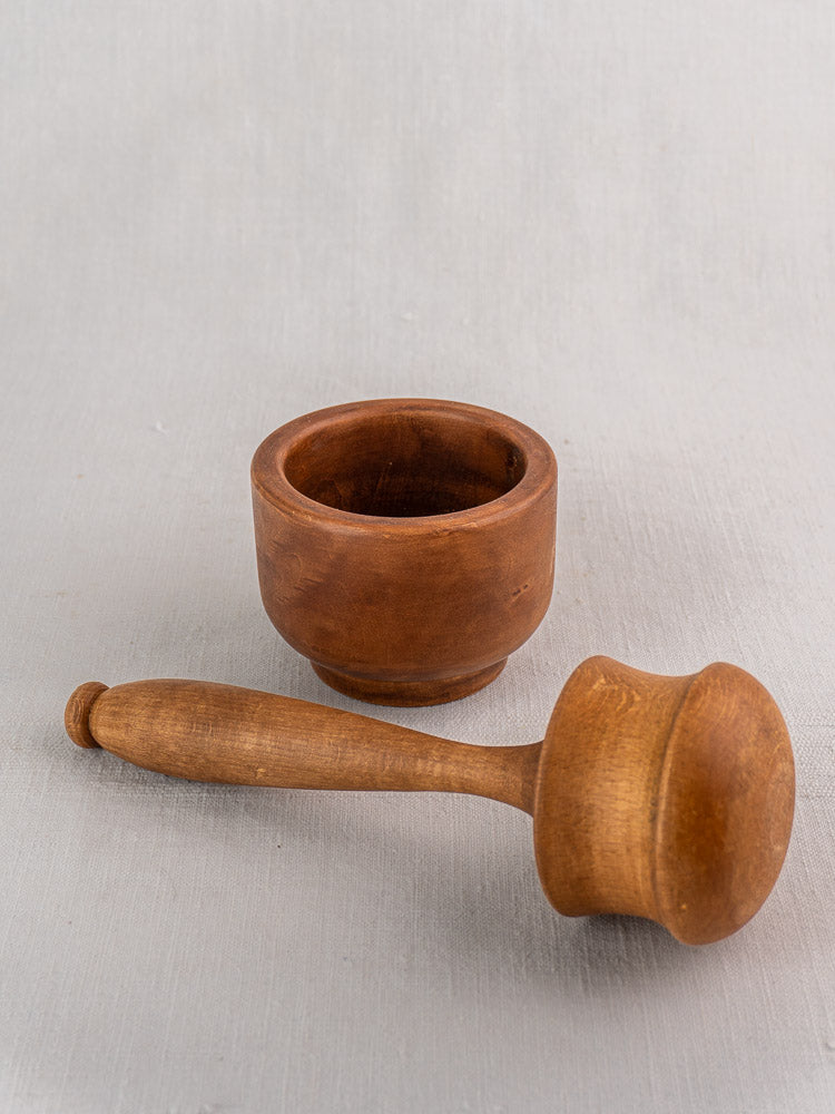 Antique French wooden mortar and pestle in turned hardwood, early to mid 20th century, on light gray surface.