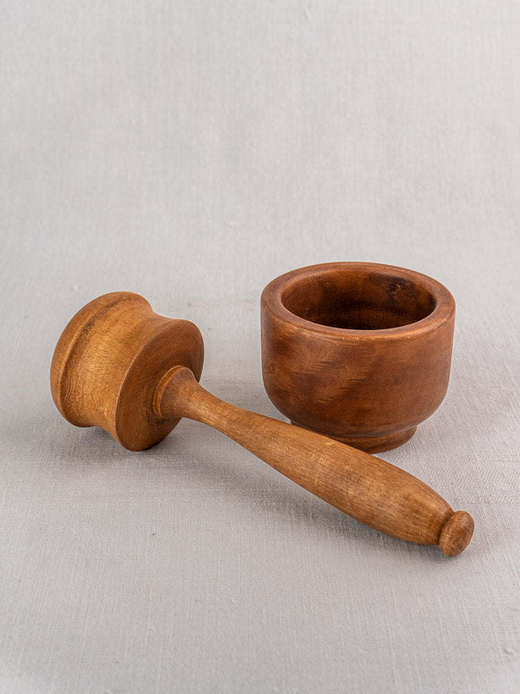 Antique French wooden mortar and pestle in smooth turned hardwood, showcasing classic country craftsmanship on a light gray surface.