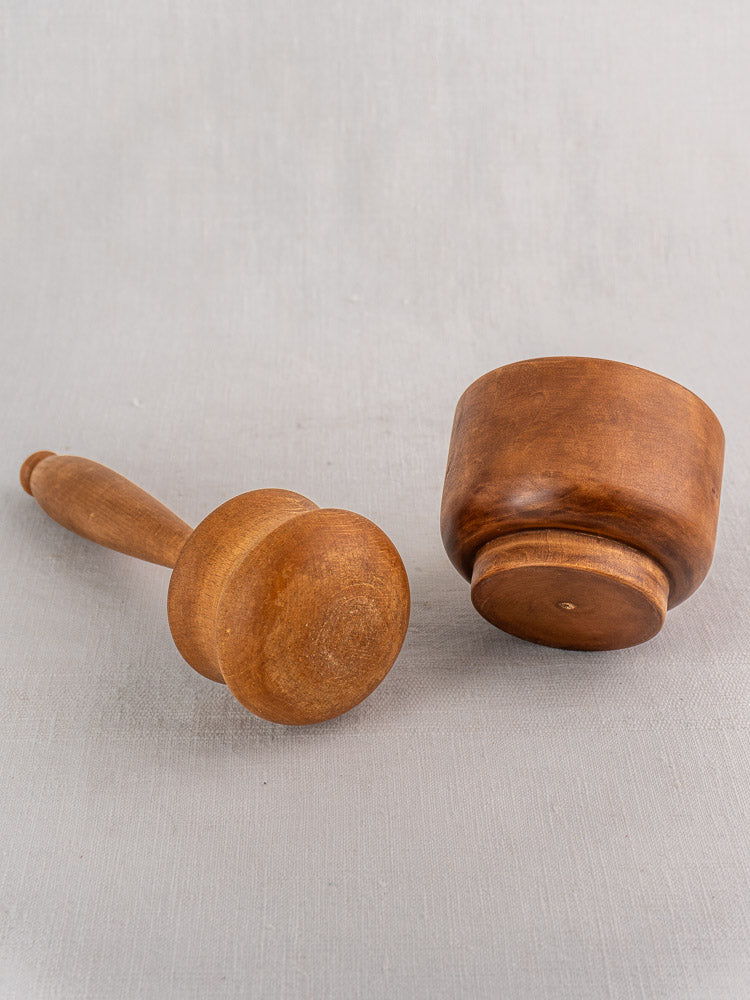 Antique French wooden mortar and pestle set in turned hardwood with smooth finish, displayed on a light gray surface.