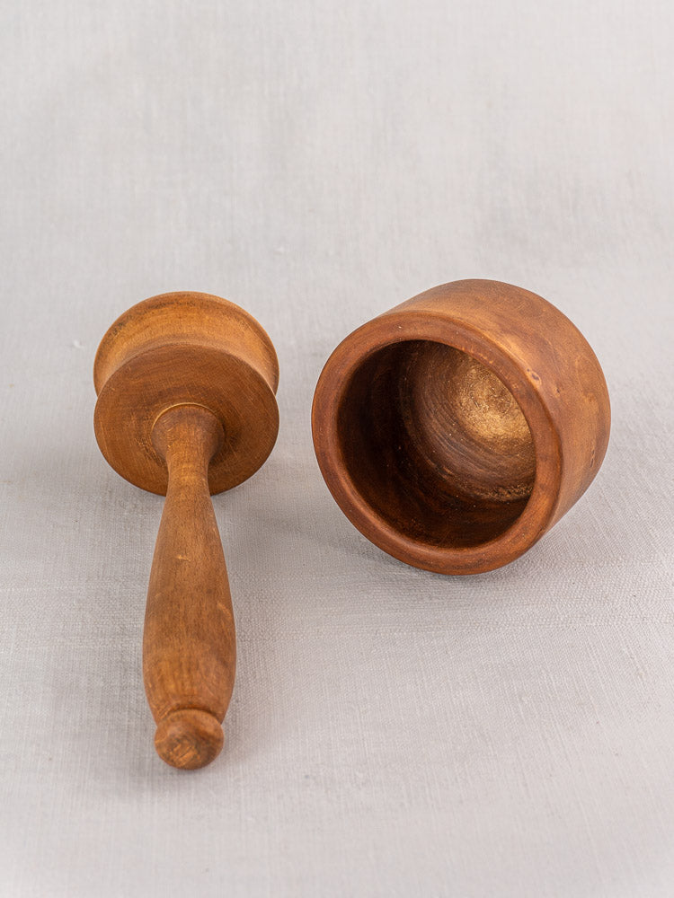 Antique French wooden mortar and pestle in turned hardwood, early-mid 20th century, on light gray surface.